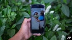 Mynor Cardona shows a photo on his cellphone of her daughter, Yenifer Yulisa Cardona Tomás, at the hospital while receiving a visit, in Guatemala City, Monday, July 4, 2022. (AP Photo/Oliver de Ros)