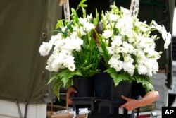 A worker brings condolence flowers to the residence of Japan's former Prime Minister Shinzo Abe, who was assassinated July 9, 2022, in Tokyo.