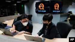 FILE - Lilibeth Frondoso, right, head of Rappler multimedia strategy and growth, talks to a staff member inside their office in Pasig city, Philippines, June 29, 2022.