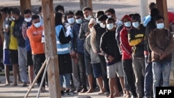 FILE - Migrants line up after disembarking on the southern Italian island of Lampedusa on May 17, 2021.