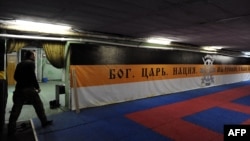 FILE - A picture taken on February 28, 2015 shows a member of the Russian Imperial Movement, a nationalist group in Russia, walking close to a banner reading "God. Tsar. Nation. We are Russians, God with us" at a training base in St. Petersburg, Russia. 