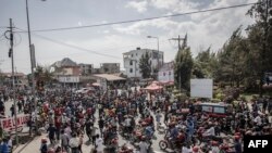 Des habitants se rassemblent au passage du convoi transportant le corps d'un militaire de la République démocratique du Congo depuis le poste frontière rwandais de Rubavu (Gisenyi) le 17 juin 2022.