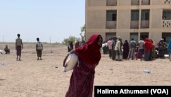 A displaced woman walks away with a food bag at the Dubti displaced peoples site in Northern Ethiopia. (Halima Athumani/VOA)