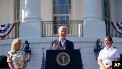 President Joe Biden speaks during a Fourth of July celebration for military families on the South Lawn of the White House, July 4, 2022, in Washington. Listening are first lady Jill Biden, left, and Navy Chaplain Lt. Chandler Irwin.