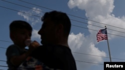 FILE - Afghan Abdul Aman Sediqi, a U.S. Special Immigrant Visa recipient, holds his son as he and his family prepare to sign a lease on an apartment following their evacuation from Afghanistan, in Houston, Texas, Aug. 26, 2021. 