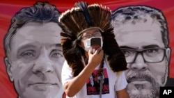 FILE - Indigenous leader Kamuu Wapichana is backdropped by a banner that show images of missing freelance British journalist Dom Phillips, left, and Indigenous expert Bruno Pereira, during a protest asking authorities to expand the search efforts for the 