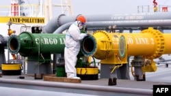 FILE - An inspection officer checks a tanker carrying imported crude oil at Qingdao port in China's eastern Shandong province, May 9, 2022.