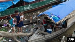 Members of an Indigenous family who temporarily lives on a boat while staying in the city, walk on a tree branch to reach the ground in Atalaia do Norte, state of Amazonas, Brazil, on June 22, 2022. 