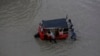 Orang-orang mendorong bajaj di jalan yang tergenang banjir setelah hujan lebat di Karachi, Pakistan, 7 Juli 2020.