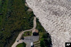 FILE - A road ends where floodwaters washed away a house in Gardiner, Mont., on June 16, 2022.