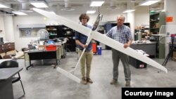 Aerospace engineering doctoral student Adrien Bouskela (left) and professor Sergey Shkarayev hold an experimental sailplane. The team hopes to one day send a version of a similar plane to Mars. (Image Credit: Emily Dieckman/College of Engineering)