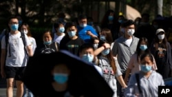 People wearing face masks walk across a crosswalk in the central business district in Beijing, June 24, 2022.