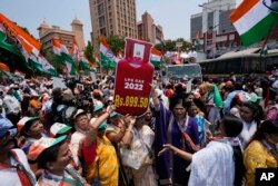 Para pekerja partai Kongres, berunjuk rasa dengan membawa gambar potongan tabung gas elpiji yang biasa mereka gunakan untuk memasak, menentang kenaikan harga bahan bakar di Mumbai, India, Rabu, 6 April 2022. (AP Photo/ Rajanish Kakade)