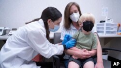 Pharmacist Kaitlin Harring, left, administers a Moderna COVID-19 vaccination to 3-year-old Fletcher Pack while he sits on the lap of his mother, McKenzie Pack, at Walgreens pharmacy Monday, June 20, 2022, in Lexington, South Carolina. 
