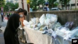 A mourner offers a flower for former Japanese Prime Minister Shinzo, at the entrance of the Liberal Democratic Party (LDP) headquarters building in Tokyo, Japan, July 10, 2022. 