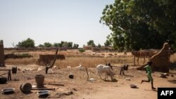 FILE - A child runs through destroyed houses in the village of Ogossagou, Mopti Region, Nov. 5, 2021.