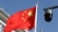 FILE - A surveillance camera overlooking a street hangs next to a Chinese flag in Beijing, China, Nov. 25, 2021. Street cameras are a primary mode of surveillance in China; more than half of the world's nearly 1 billion surveillance cameras are in China.