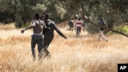 FILE: Migrants run on Spanish soil after crossing the fences separating the Spanish enclave of Melilla from Morocco in Melilla, Spain, June 24, 2022.