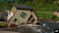 FILE - A house sits in Rock Creek after floodwaters washed away a road and a bridge in Red Lodge, Mont., on June 15, 2022. Climate experts and meteorologists say modeling programs used to predict storms aren't keeping up with increasingly extreme weather.