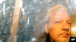 FILE: Buildings are reflected in the window as WikiLeaks founder Julian Assange is taken from court, where he appeared on charges of jumping British bail seven years ago, in London, May 1, 2019.