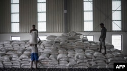 FILE - Men carry a bags of wheat in a U.N. storehouse on the outskirts of Semera, Afar region, Ethiopia, May 15, 2022. A European Union official says there is not enough fuel to distribute aid throughout Tigray, while Ethiopian officials deny the claim.