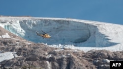 A rescue helicopter flies above the Marmolada glacier, near Canazei, Italy, on July 4, 2022, one day after part of the glacier collapsed, killing seven people.