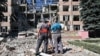 Workers stand outside a partially destroyed educational and laboratory building of a college hit the day before by a rocket in Kharkiv on June 21, 2022. 