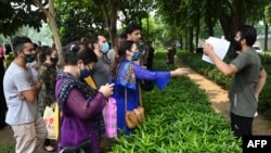 FILE - Afghan people gather outside the embassy of the United States of America in New Delhi on Aug. 19, 2021, to submit documents to apply for a visa. The cost of applying for a visa is prohibitive for many Afghan students wanting to study in the U.S.