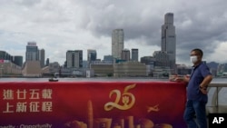 A man poses for a photograph next to a banner to mark the 25th anniversary of Hong Kong handover to China in Hong Kong, June 22, 2022.