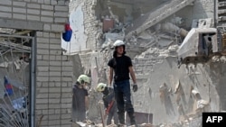 Rescuers work on the ruins of a school building, partially destroyed by two rockets in the Ukrainian city of Kharkiv on June 28, 2022. 