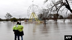 FILE - People look at a flooded park due to torrential rain in the Camden suburb of Sydney, Australia, July 3, 2022.