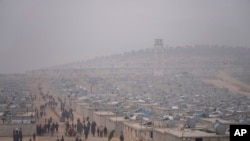 FILE - Syrians walk in a refugee camp for displaced people run by the Turkish Red Crescent in Sarmada district, north of Idlib city, Syria, Nov. 26, 2021.