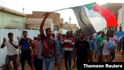 FILE - Sudanese protesters chant slogans and wave their national flag as they demonstrate against the ruling military council, in Khartoum, June 27, 2019. 