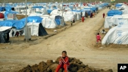 A Syrian Kurdish refugee plays on a pile of dirt in the Dumiz refugee camp in northern Iraq, Feb. 15, 2013.