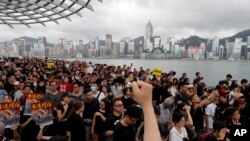 FILE - Protesters march near the skyline of Hong Kong, July 7, 2019. China’s central government has dismissed Hong Kong pro-democracy protesters as clowns and criminals while bemoaning growing violence surrounding the monthslong demonstrations.