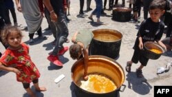 A child picks food from the bottom of a pot at a U.N. Relief and Works Agency for Palestine Refugees school in the Jabalia camp for Palestinian refugees in the northern Gaza Strip on June 17, 2024.