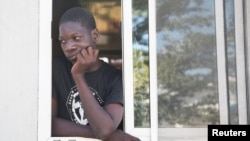 A man looks out from a window as people fleeing from violence after the murder of a local gang leader camp out in the courtyard of Cite Soleil's town hall, in Port-au-Prince, Haiti, Dec. 7, 2019. 
