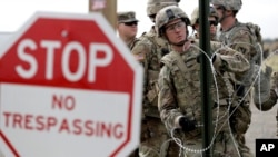 Members of the U.S Army place razor wire for a temporary encampment for the troops near the U.S.-Mexico International bridge, Nov. 4, 2018, in Donna, Texas.