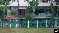 FILE - Bangladeshi policemen walk past the Holey Artisan Bakery, the site of a militant attack, in Dhaka's Gulshan area, Bangladesh. 