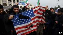 FILE - Protesters deface an American flag during an anti-U.S. rally over a U.S. drone strike in Iraq that killed Iranian Revolutionary Guard Gen. Qassem Soleimani, in Tehran, Iran, Jan. 3, 2020.