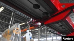 FILE - A worker in protective suit disinfects a factory before it resumes operation on Feb. 10 following an extended Lunar New Year holiday caused by the novel coronavirus outbreak, in Lianyungang, Jiangsu province, China, Feb. 9, 2020.
