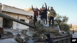 Syrian opposition supporters stand atop a captured Syrian army tank in the town of Maarat al-Numan, southwest from Aleppo, Nov. 30, 2024.