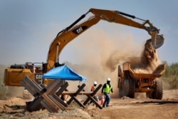 Government contractors remove existing Normandy barriers that separate Mexico and the United States, in preparation for a section of Pentagon-funded border wall along the Colorado River, Sept. 10, 2019, in Yuma, Ariz.