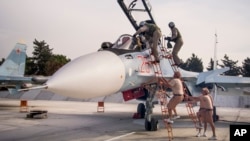FILE - Russian air force pilots, assisted by ground personnel, climb into their fighter jet at Hemeimeem airbase, Syria, Oct. 22, 2015.