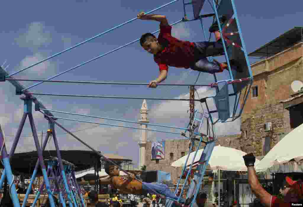 Children ride swings during Eid al-Fitr in the port city of Sidon, southern Lebanon, August 8, 2013.