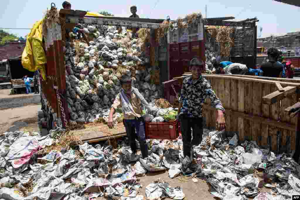 Children unload a truck carrying papayas at Okhla wholesale vegetable market in New Delhi, India.