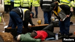 Police officers work to remove protesters who had chained themselves to a homemade coffin close to the entrance of the IGas exploratory gas drilling site at Barton Moss, near Manchester, northern England, March 6, 2014