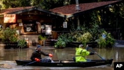 Kevin Ozorkiewicz, left, and neighbor John Phillips paddle a canoe at the flooded Mirabel RV Park & Campground after a major storm in Forestville, Calif., Sonoma County, Nov. 23, 2024. 