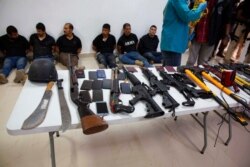 FILE - Suspects in the assassination of Haiti's President Jovenel Moise are shown to the media, along with the weapons and equipment they allegedly used in the attack, in Port-au-Prince, Haiti, July 8, 2021.