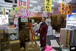 Bi Yan'ao stands in the midst of a cosmetic shop he is clearing out after eviction orders were handed down in Beijing, Nov. 27, 2017.